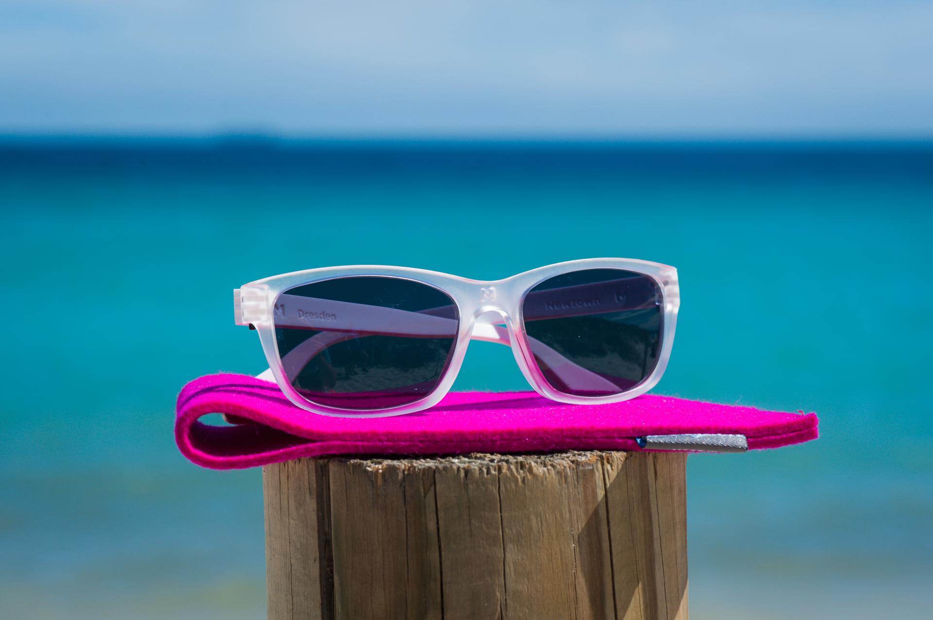 Polarised Dresden Vision Australia sunglasses resting on a wooden post by the ocean to demonstrate effective glare reduction for Australian beach days.