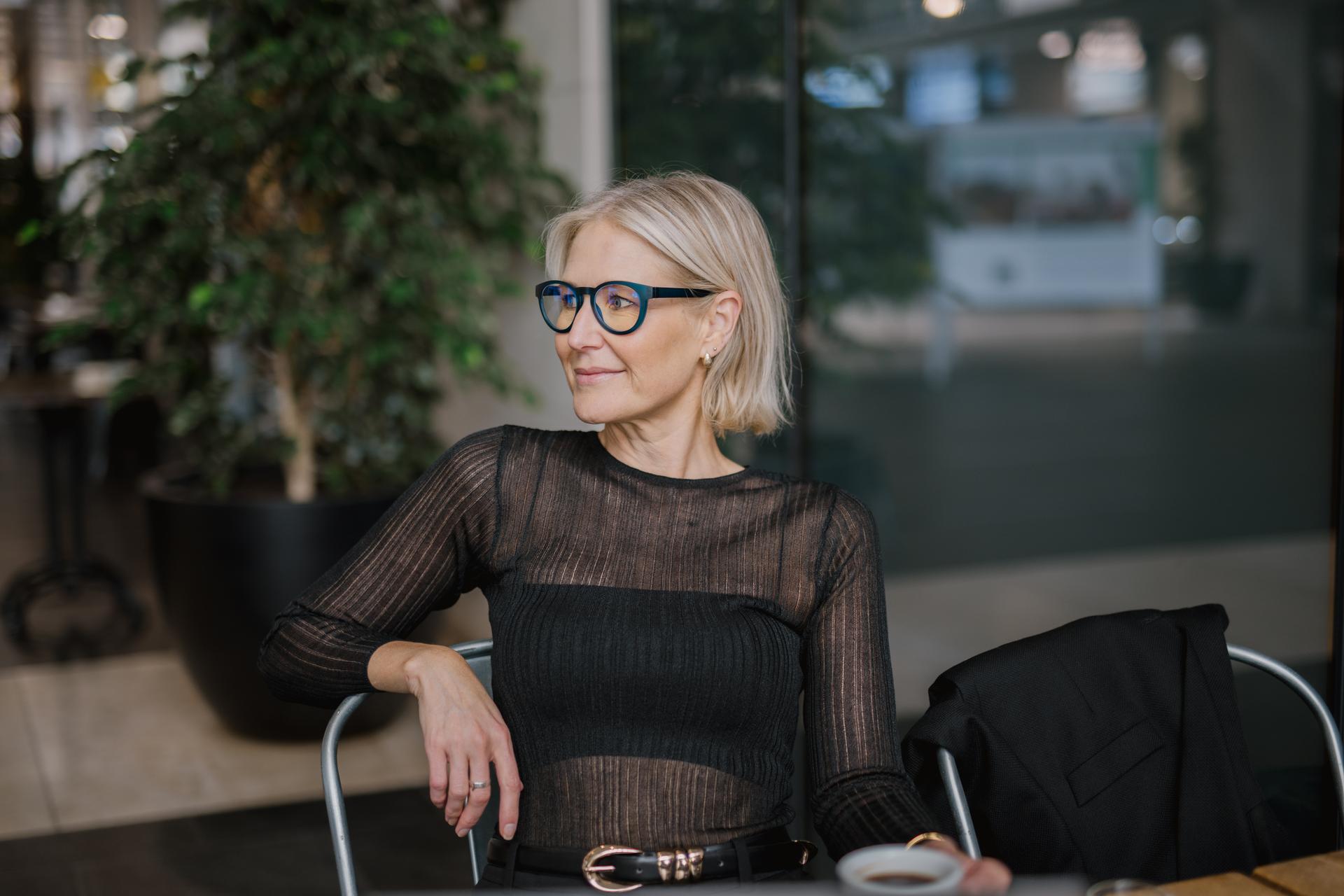 A stylish woman with short blonde hair and Dresden Vision New Zealand glasses with a multi-colored frame.