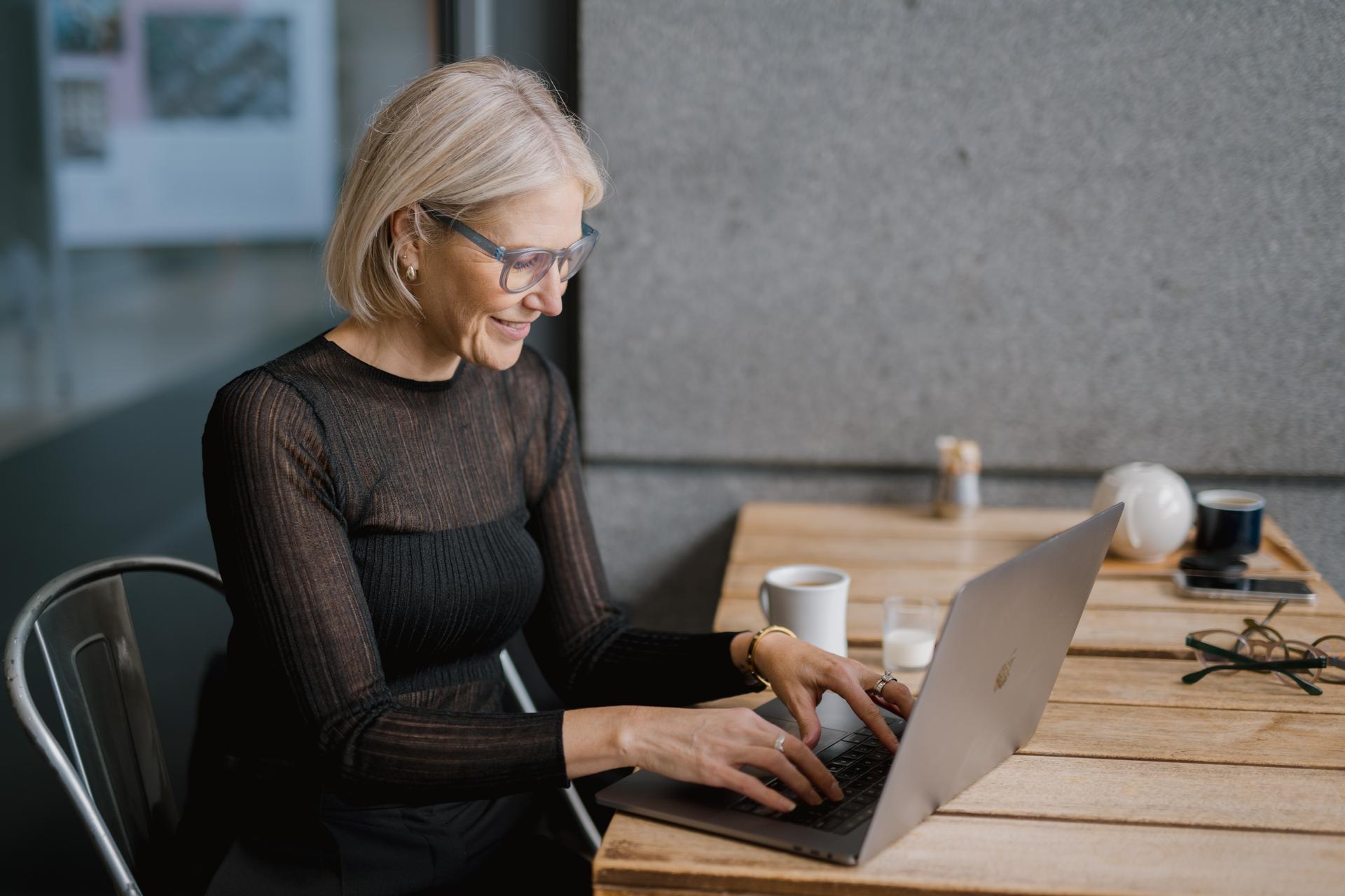 Woman wearing Dresden Vision Australias blue light filter glasses while working on her laptop.