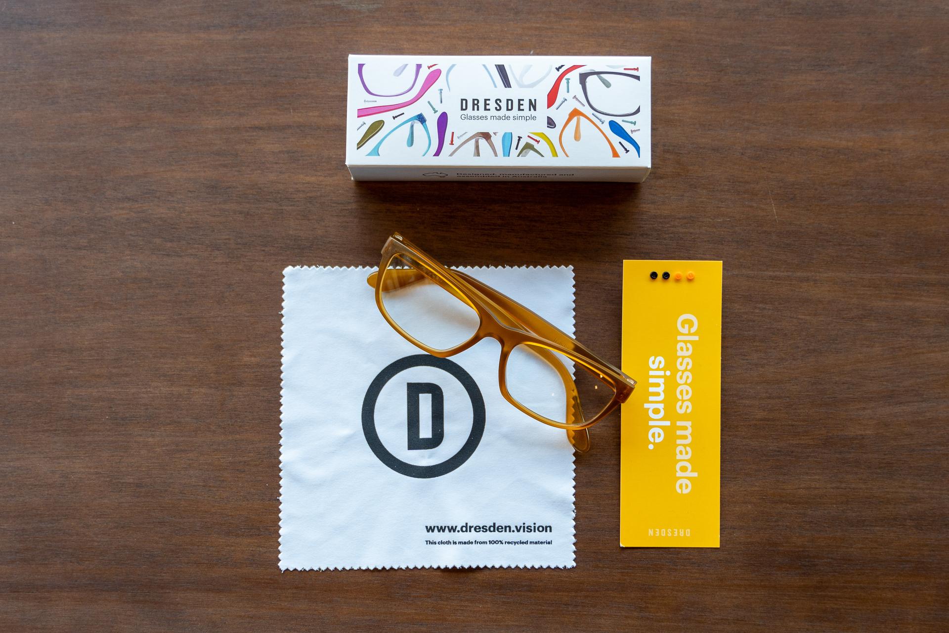 Top view of Dresden Vision New Zealand glasses and accessories, including a cleaning cloth and packaging, showcasing sustainable eyewear.