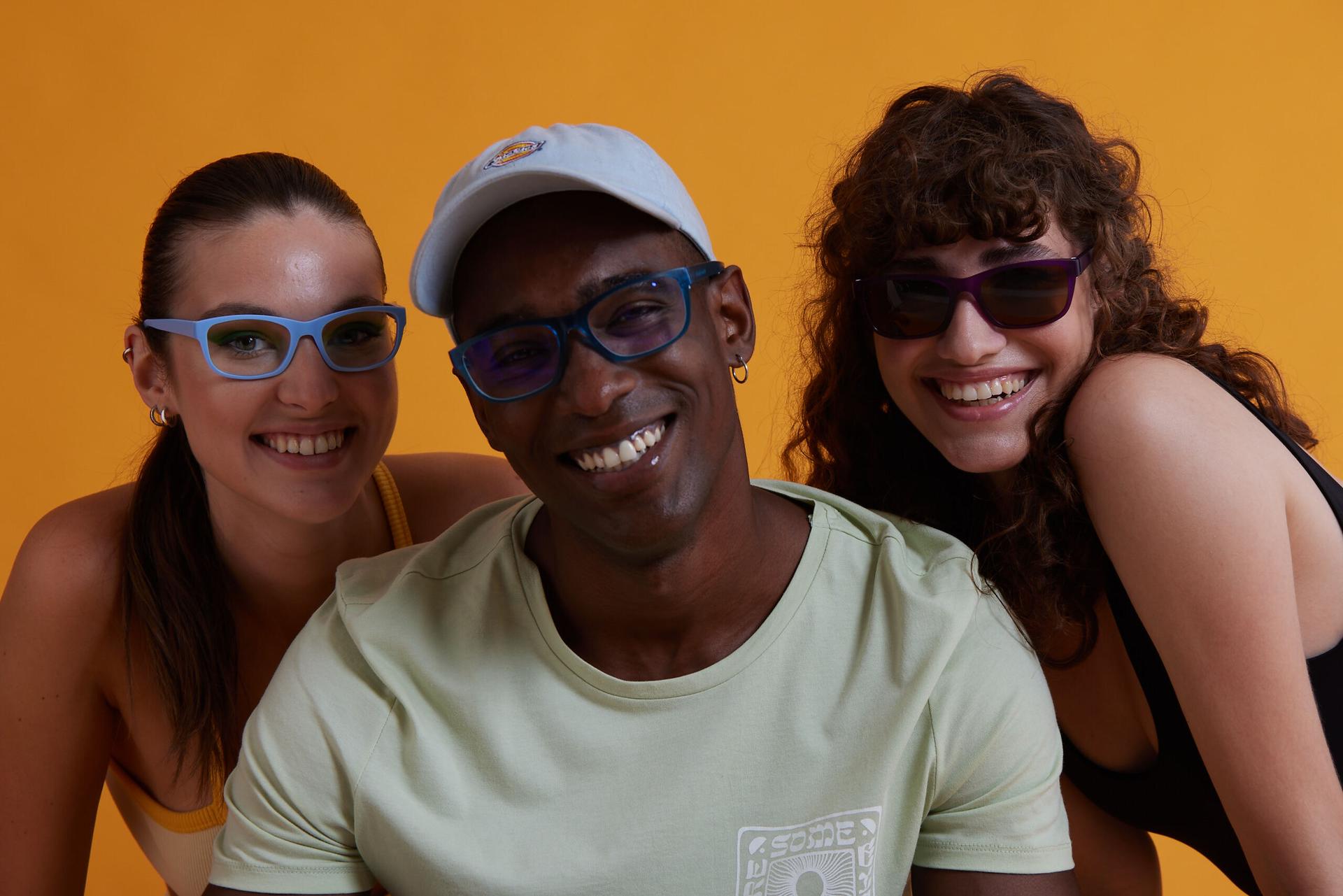 Three people smiling while wearing glasses, showing confidence and clear vision. Learn how to improve your eyesight with proper eyewear.