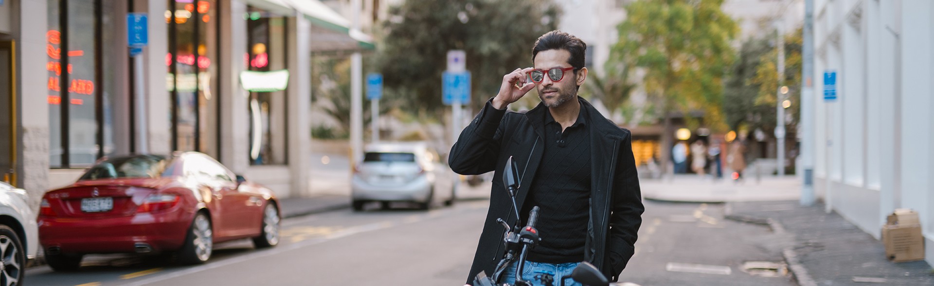 Confident man with mirrored sunglasses and casual streetwear beside motorbike, featuring Dresden Vision United States.