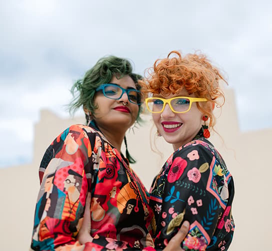 Dressed in bold patterns, two friends showcase their Dresden Vision New Zealand womens glasses, adding a pop of color with yellow and blue frames.