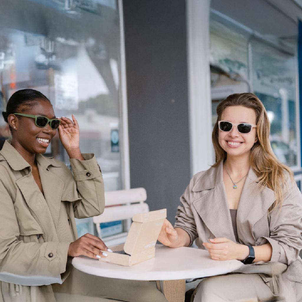 Two women smiling outdoors and wearing stylish women's sunglasses from Dresden Vision Australia, showcasing eco-friendly eyewear options.