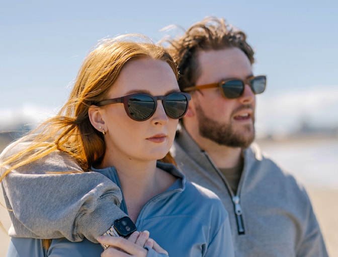 Woman and man in Dresden Vision Canada prescription sunglasses, looking ahead in a bright coastal environment