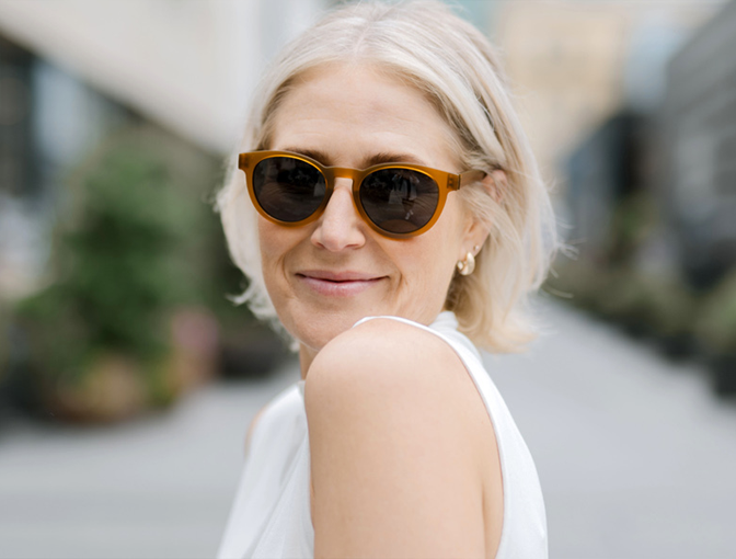 A woman outside wearing amber-frame Dresden Vision United States progressive sunglasses, offering clear and comfortable vision across all distances under sunny conditions.
