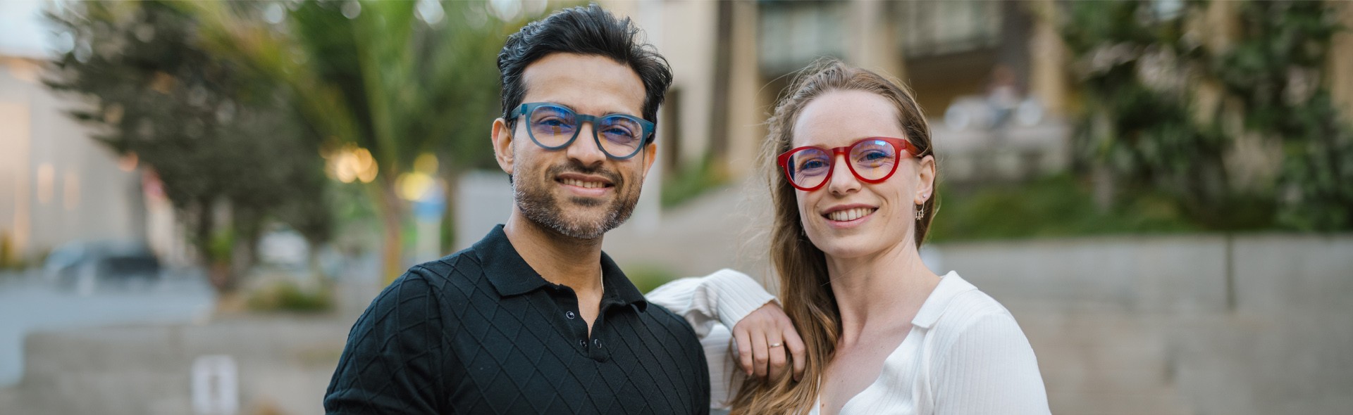 A man and woman wearing vibrant Dresden Vision New Zealand progressive glasses, showcasing the brand’s distinctive blue and red modular frames designed for near, intermediate, and distance vision.